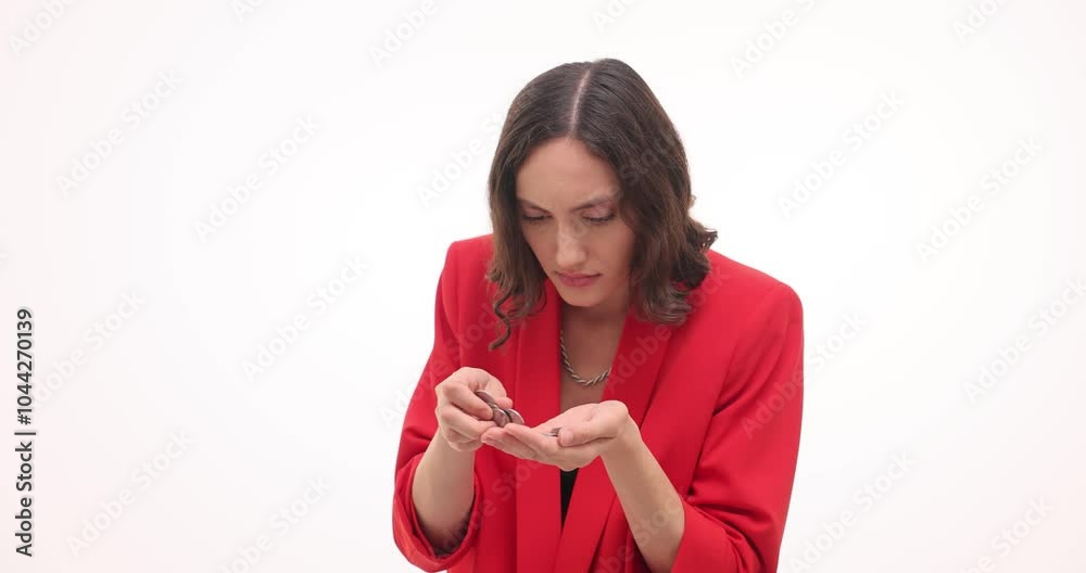 Greedy businesswoman in red blazer coins coins in palm on white background. Emotional female hides cash money in hand turning around slow motion