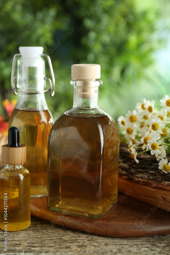 Different tinctures in bottles and chamomile flowers on wooden table Different tinctures in bottles and chamomile flowers on wooden table