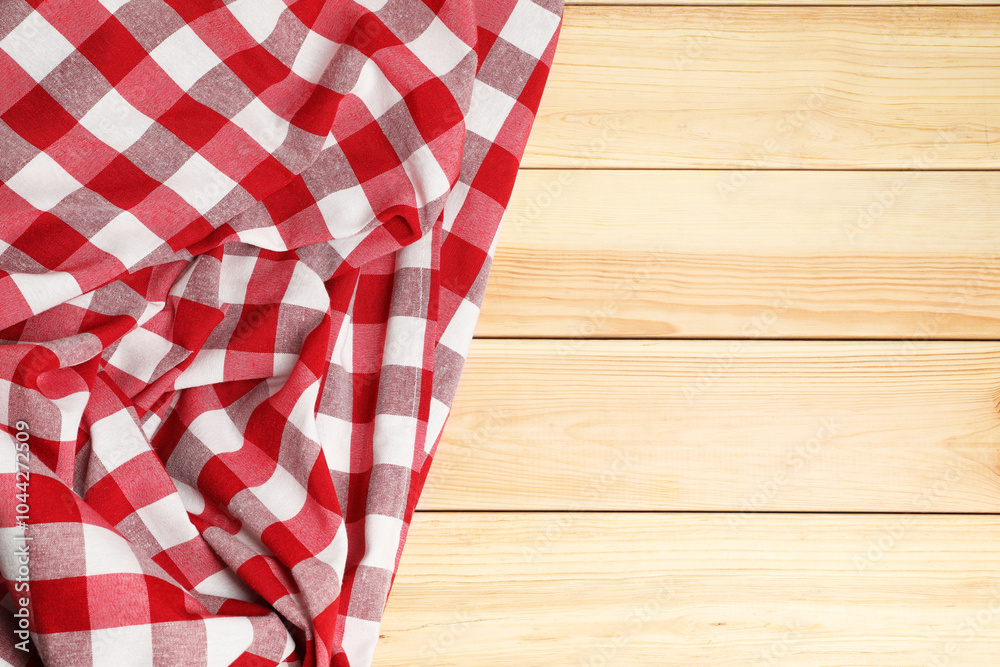 Obraz premium Crumpled tablecloth with checkered pattern on light wooden table, top view. Space for text