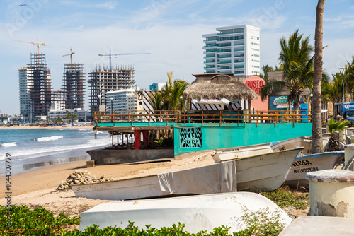 Artisanal fishing boats on the beach, in front of a beachfront bar and restaurant, in Mazatlan, Mexico photo