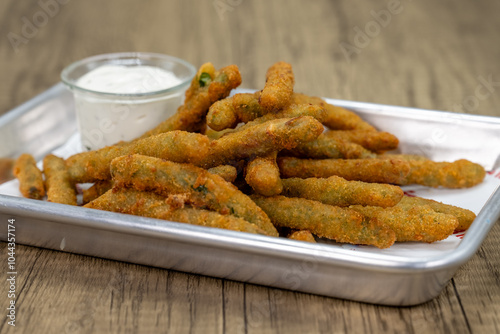 Crispy order of deep fried breaded green beans on a tray with ranch dipping sauce