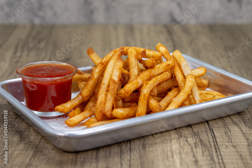 Crispy order of french fries on a tray with ketchup dipping sauce photo