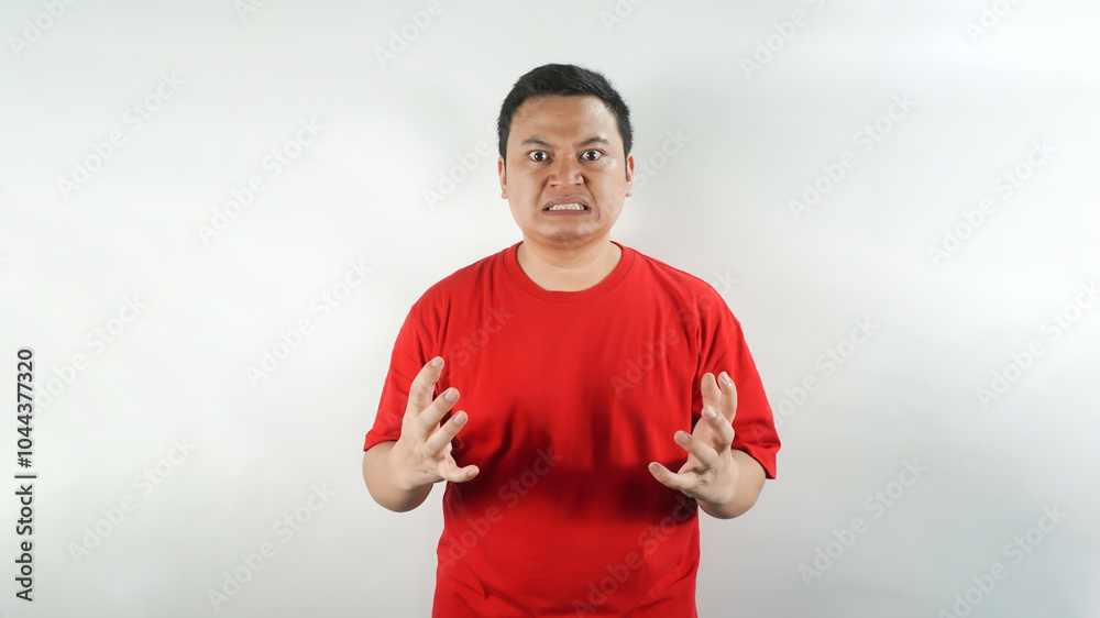 Naklejka premium A young Indonesian man wearing a red t-shirt with an angry face facing forward