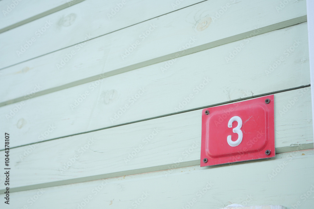 House Number 3 displayed prominently on beautiful Weathered Green Wood Paneling exterior House Number 3 displayed prominently on beautiful Weathered Green Wood Paneling exterior