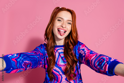 Photo of lovely young lady take selfie photo stick tongue out dressed stylish blue colorful garment isolated on pink color background photo