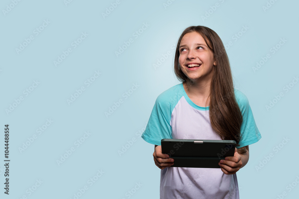 Smiling girl gazing upwards while holding tablet Smiling girl gazing upwards while holding tablet