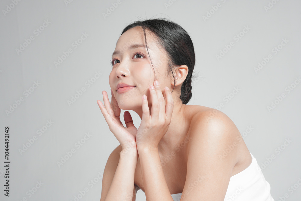 グレー背景で撮影をした若いアジア女性のスタイリッシュなスキンケアイメージ