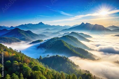 Scenic view of misty mountains in sunlight against clear blue sky