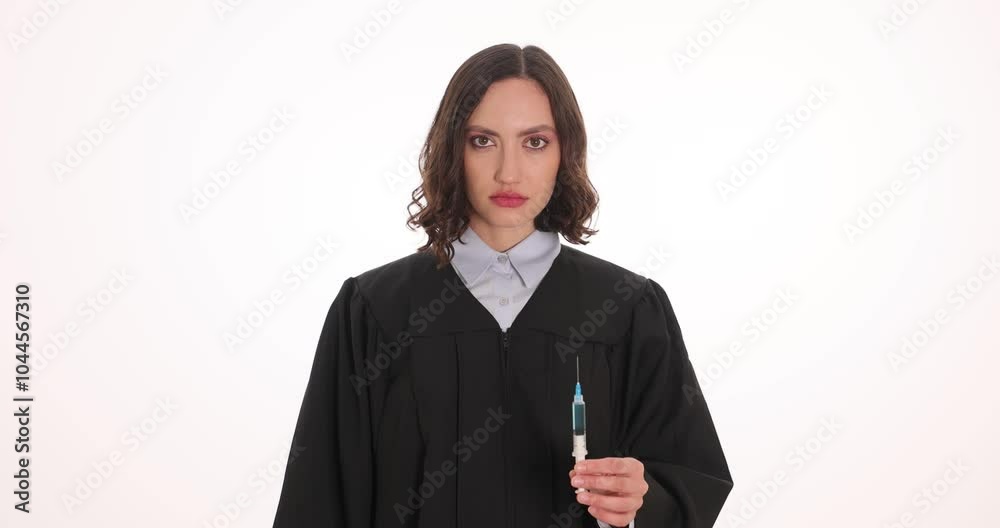 Female judge in black gown holds syringe showing handcuffs on white background. Woman embodies authority in legal system and concept of justice Female judge in black gown holds syringe showing handcuffs on white background. Woman embodies authority in legal system and concept of justice