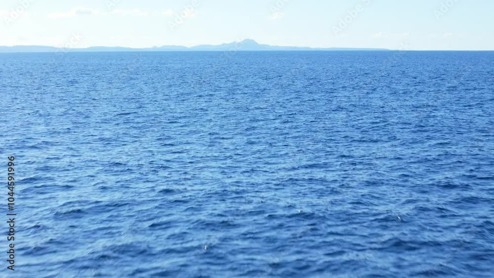 Steady aerial dolly over ocean with distant view of Curaçao hills, capturing tranquil and vast blue waters Steady aerial dolly over ocean with distant view of Curaçao hills, capturing tranquil and vast blue waters