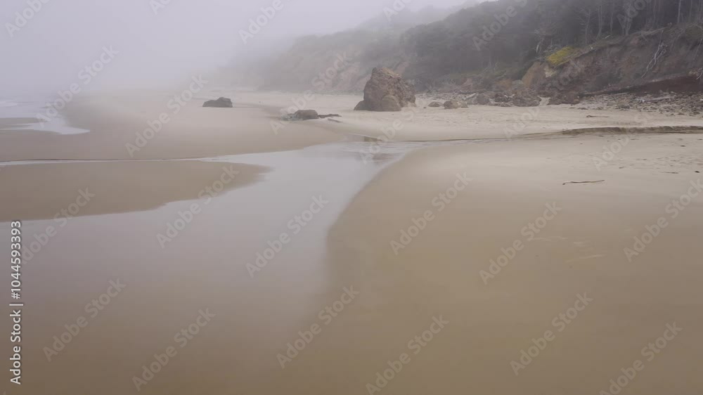 Rainy day on Oregon Coast. Low proximity drone flight over wet sand and rocks covered by fog. Mystical dolly in aerial Rainy day on Oregon Coast. Low proximity drone flight over wet sand and rocks covered by fog. Mystical dolly in aerial