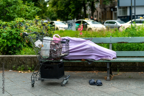 Homeless lying on city bench with a shopping cart and   blanket in the heart of urban life