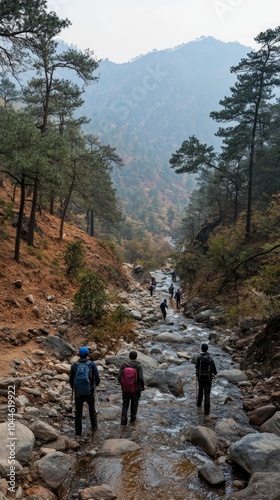 A group of hikers navigate through a rocky stream in the mountains, surrounded by lush trees and the serene atmosphere of nature