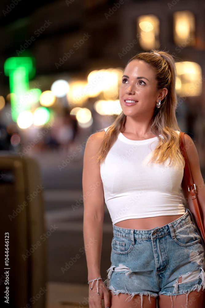 Young woman is smiling while looking up at the lights in times square at night Young woman is smiling while looking up at the lights in times square at night