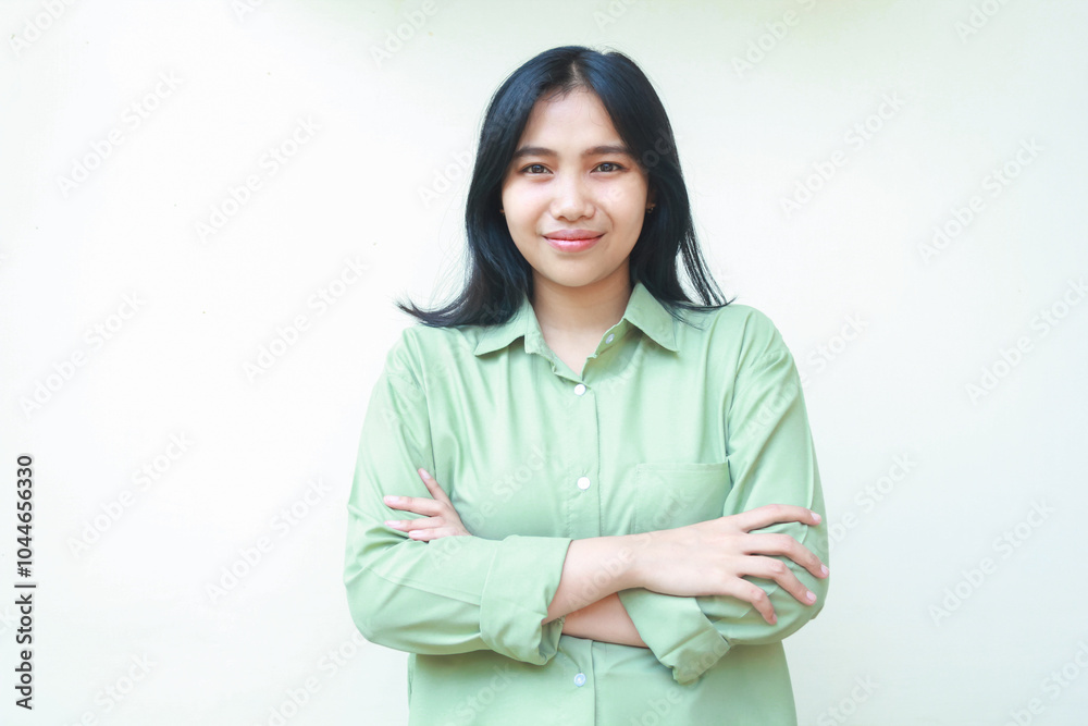 Fototapeta premium pleased successful dark hair asian woman wearing green over size shirt cross hands and looking at camera with confident face expression standing over isolated white background