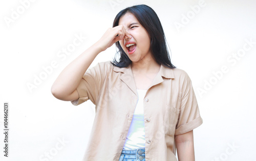 asian woman touching her nose smelling something stinky wearing casual brown clothes isolated on white background