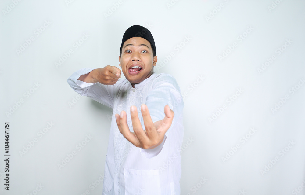 funny asian muslim man pointing to empty palm posing holding bowl isolated on white background funny asian muslim man pointing to empty palm posing holding bowl isolated on white background