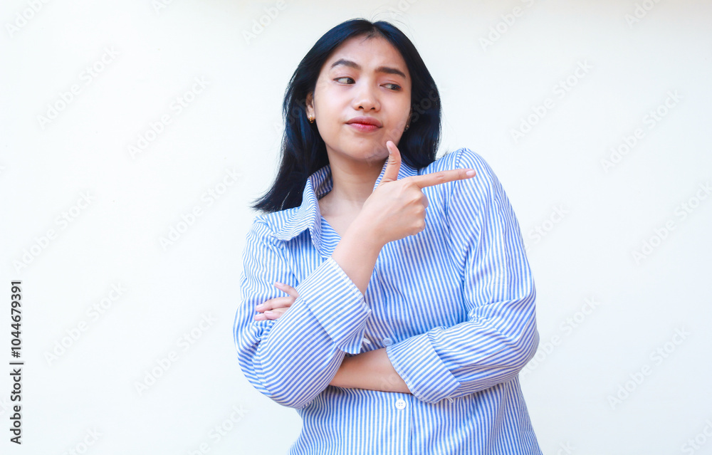 confused asian woman wearing casual stripes shirt pointing finger to empty space thinking choices standing over isolated white background confused asian woman wearing casual stripes shirt pointing finger to empty space thinking choices standing over isolated white background