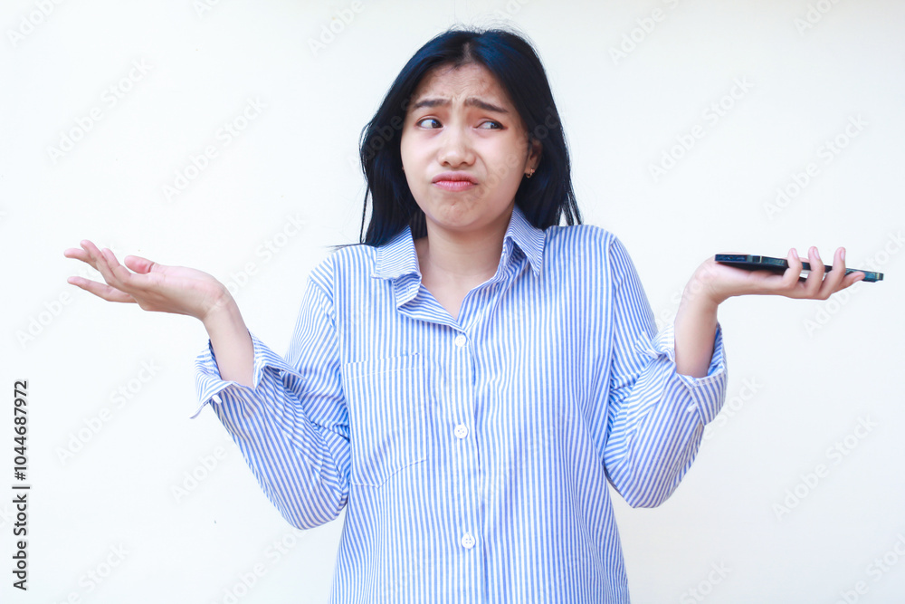 confused asian woman using mobile phone raising palms show do not know gesture with annoyed face expression wear blue striped shirt isolated white background confused asian woman using mobile phone raising palms show do not know gesture with annoyed face expression wear blue striped shirt isolated white background