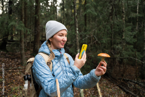 Woman using technology to identify mushrooms in a forest photo