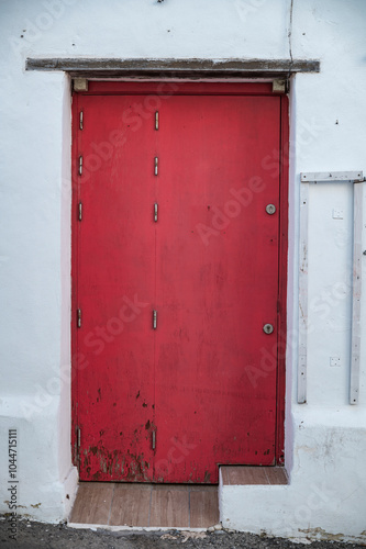 Red wooden door on white wall in Conil de la Frontera, Spain photo