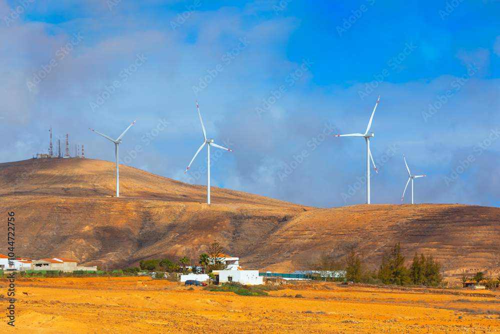 Wind turbines at Fuerteventura, Canary Islands Spain. Scenic view of multiple wind turbines standing tall on a hill against a blue sky