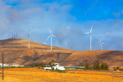 Obraz na płótnie Wind turbines at Fuerteventura, Canary Islands Spain. Scenic view of multiple wind turbines standing tall on a hill against a blue sky w salonie