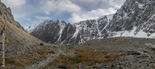 High resolution panoramic image of mountain landscape. Stone ground, thin mountain pathway,  steep slopes, gray rocky vertical mountains in Altai nature of golden autumn.