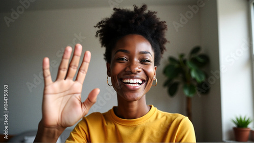 Happy black woman waving during video call at home