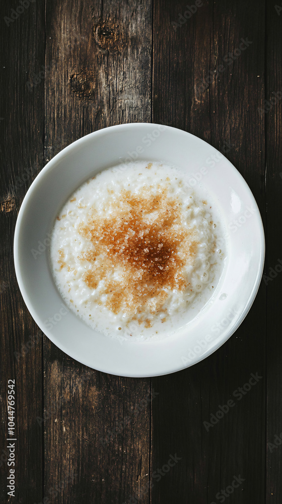 Rice pudding with cinnamon powder in a white bowl, presented on a wooden rustic table Rice pudding with cinnamon powder in a white bowl, presented on a wooden rustic table