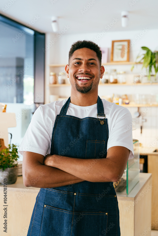 Fototapeta premium Bakery, happy portrait of hispanic black man in cafe ready for serving pastry, coffee and baked foods. Restaurant, coffee shop and confident waiter barista by counter for service, help and welcome