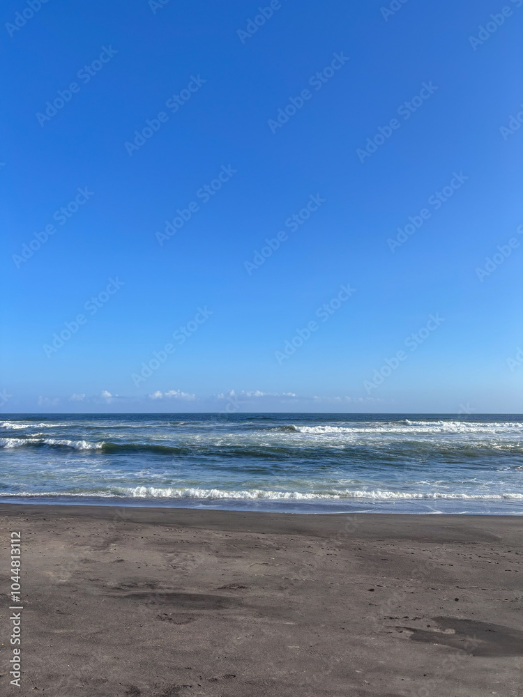 A beach with a clear blue sky and a few clouds A beach with a clear blue sky and a few clouds