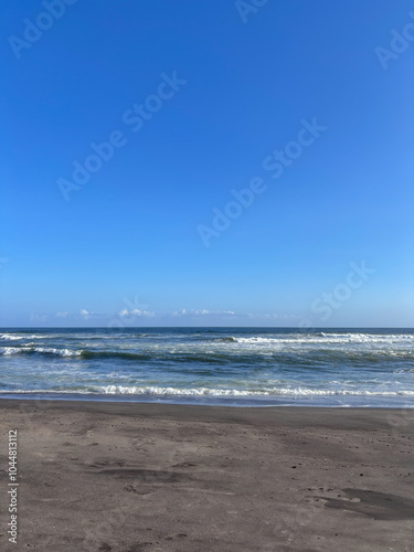 A beach with a clear blue sky and a few clouds