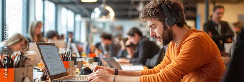 Focused man working on laptop in modern office environment, wearing headphones. workspace is vibrant with colleagues collaborating in background, creating dynamic atmosphere