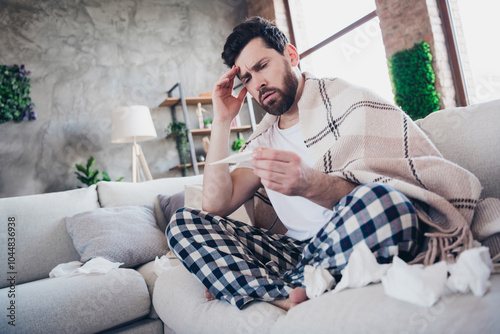 Photo of young ill man wearing pajama staying home feeling unwell suffer covid19 symptom sitting on sofa living room indoors