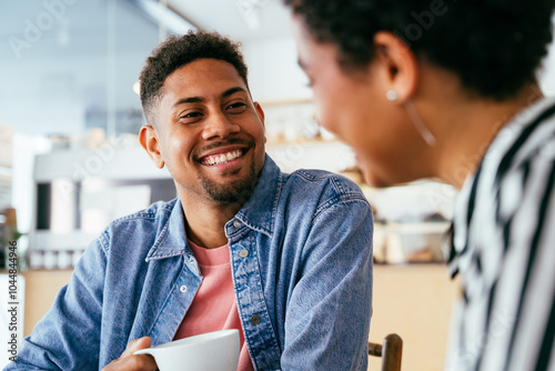Beautiful young mixed race couple bonding and  sitting in a bar cafeteria - Pretty cheerful african-american friends relaxing in a pastry bakery coffee shop