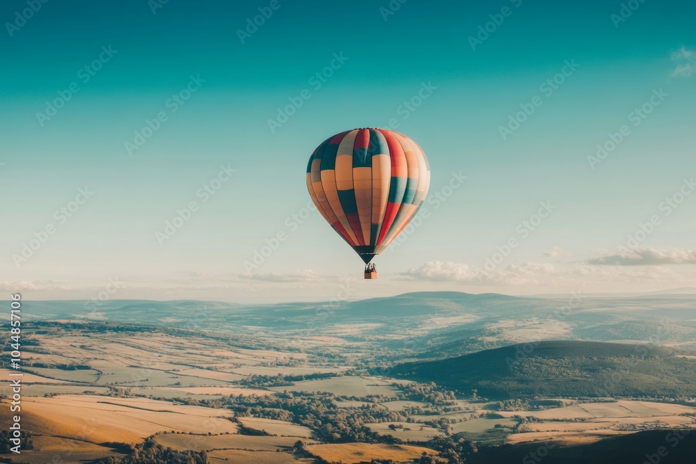 Obraz premium A vibrant hot air balloon floats gracefully above rolling hills. The colorful design adds joy to the scenic view. Perfect for travel and adventure themes. Generative AI