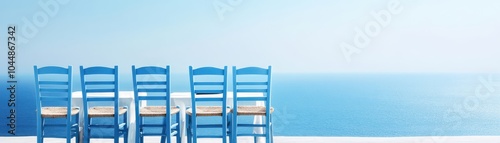 Row of blue chairs overlooking a serene ocean, perfect for relaxation and escape to a tranquil seaside setting.