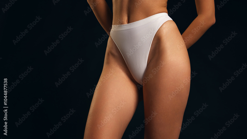 Obraz premium Close-up of fit, athletic female body in white lingerie against black studio background. Tanned, well-kept skin. Concept of female health dieting, natural beauty, wellness. Ad