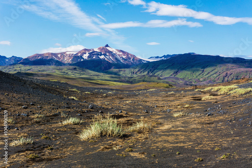 Fotografie Remote area of volcanic black sand desert wasteland with snow mountains on horizont, sharp peak of Ymir and Tindfjallajokull glacier when hiking Laugavegur trail between Emstrur Thorsmork, Iceland