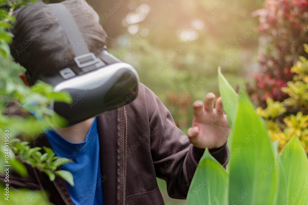 Fototapeta premium Asian highschool boy explores nature outside the classroom, observing trees and plants by using VR headsets with immersive technology to study details of leaves and bark up closely, soft focus.