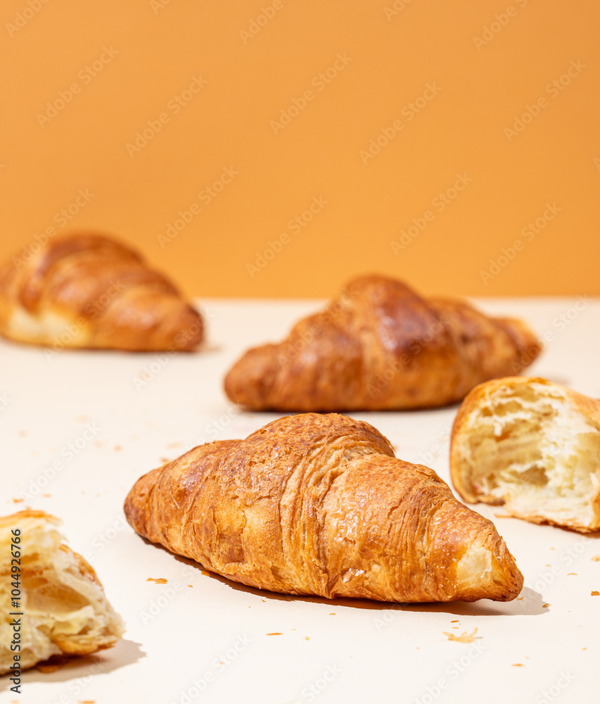 Fresh croissants on yellow and orange background. Creative trendy layout and healthy food or french breakfast concept Fresh croissants on yellow and orange background. Creative trendy layout and healthy food or french breakfast concept
