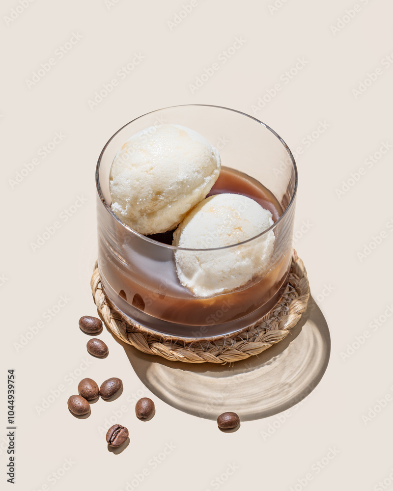 Affogato coffee with vanilla ice cream scoops and espresso in a glass on a light background with coffee beans and shadow. Affogato coffee with vanilla ice cream scoops and espresso in a glass on a light background with coffee beans and shadow.
