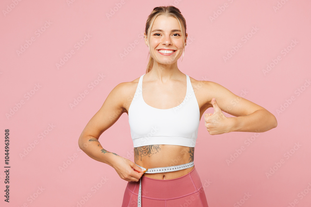 Young smiling woman wear white top casual clothes hold measure tape on waist show thumb up isolated on plain pastel light pink background. Proper nutrition healthy fast food unhealthy choice concept. Young smiling woman wear white top casual clothes hold measure tape on waist show thumb up isolated on plain pastel light pink background. Proper nutrition healthy fast food unhealthy choice concept.