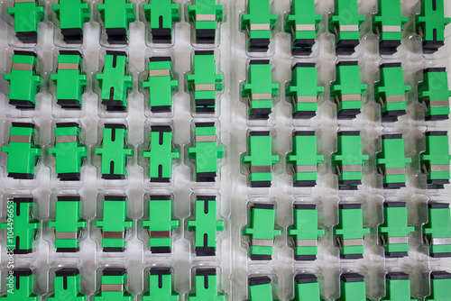 Optical adapters with different connectors in plastic blisters on the table, a batch of goods	
 photo