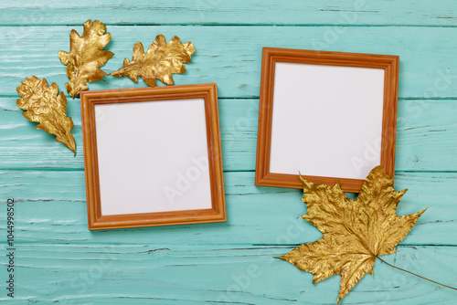 Two square frames with space for text or images, decorated with golden oak and maple leaves against an old turquoise wooden wall.