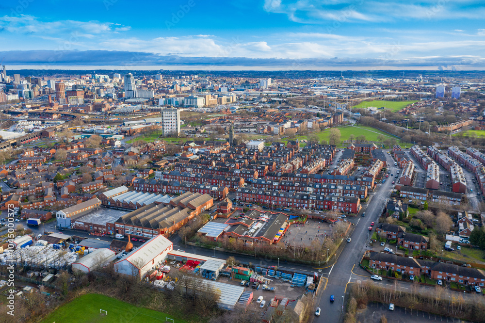 Obraz premium Aerial photo of the town of Hunslet in Leeds West Yorkshire in the UK, showing roads and rows of residential houses taken in the winter time with the Leeds city centre in the background