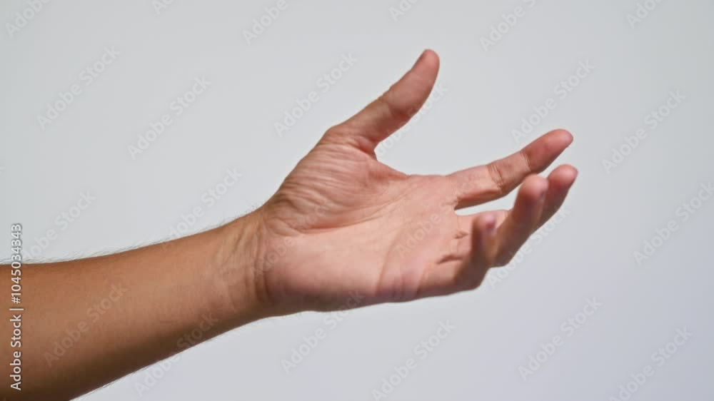 Man's hand gesturing against gray background, close-up detail highlighting male gesture and open palm motion in soft lighting Man's hand gesturing against gray background, close-up detail highlighting male gesture and open palm motion in soft lighting