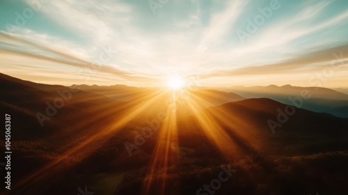 The image showcases a beautiful sunrise with radiant golden rays gently illuminating the mountain landscape, creating a serene and majestic morning atmosphere.