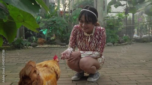 Indonesian girl surprised by an aggressive chicken encounte photo